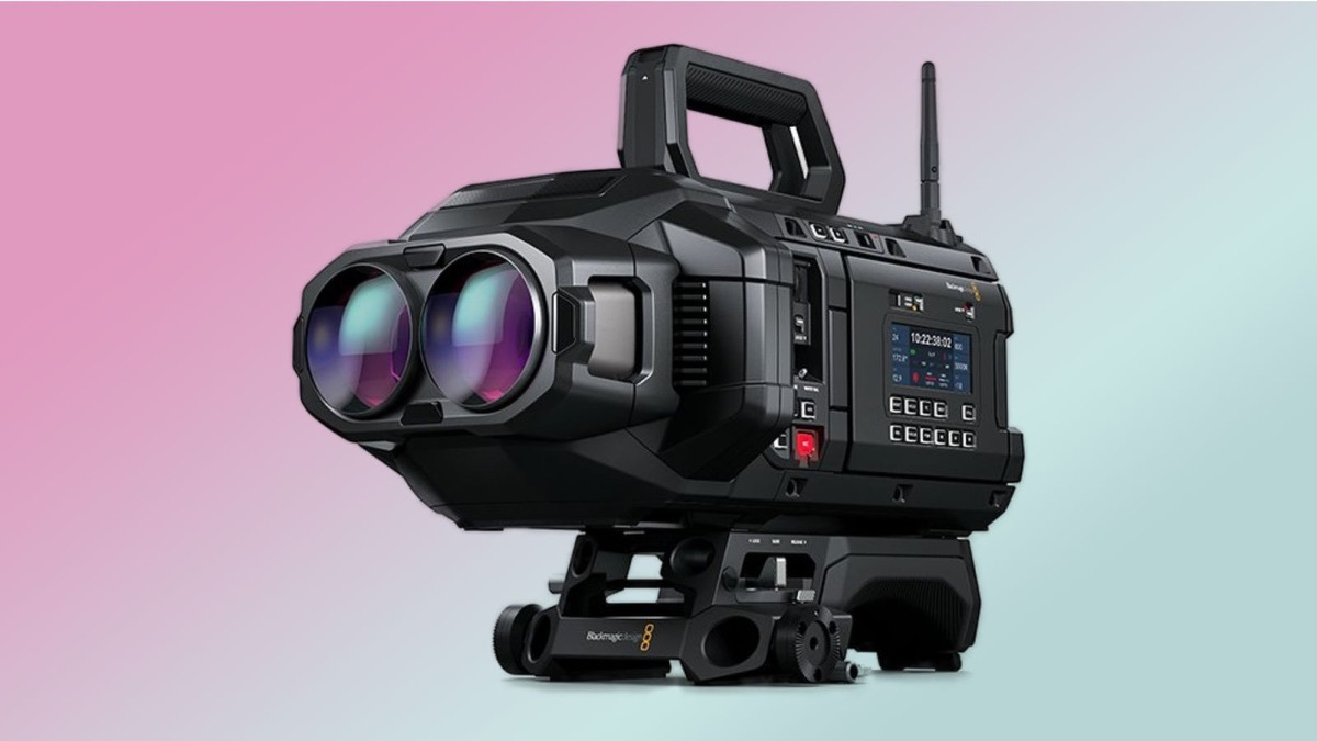 Blackmagic URSA Cine Immersive 100G camera shown in three-quarter view, twin stereoscopic lenses on a rugged black body with timecode display, antenna, and tripod mount, on a pink-to-teal gradient background